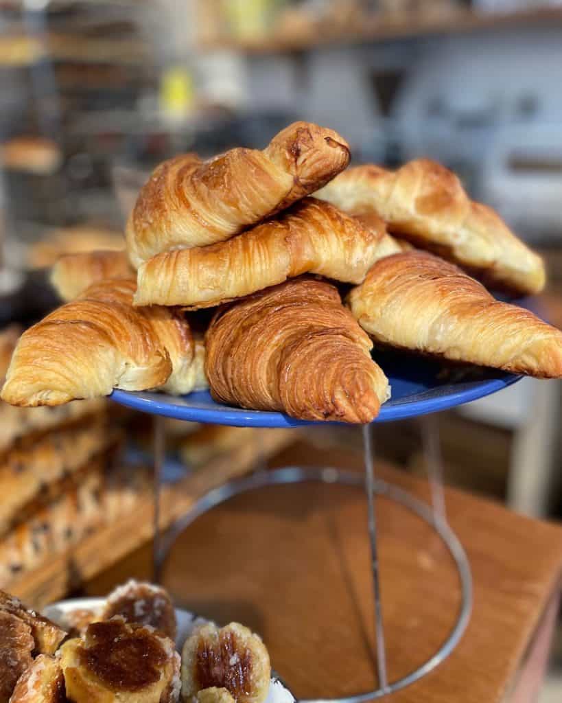 a blue plate is piled with butter croissants in a Paris bakery