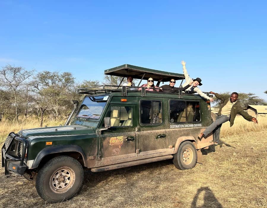 Midlife women in a safari jeep on a group tour in Tanzania. A male guide is also pictured in the jeep.