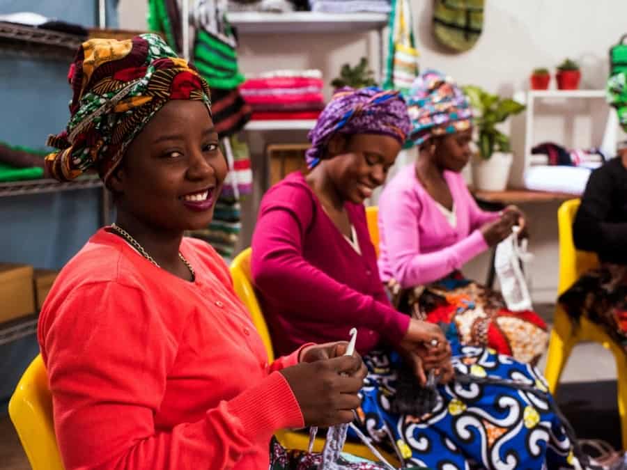 African women sit together and work on a weaving project
