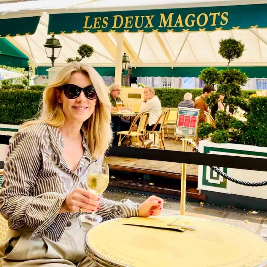 Susan Heinrich holds a glass of white wine at Les Deux Magots cafe in Paris