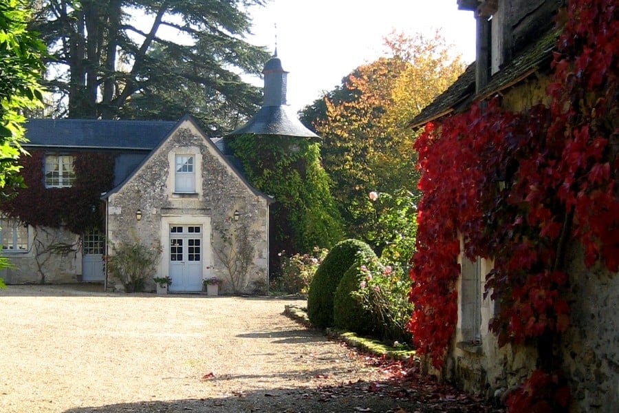 Autumn leaves and a country house beyond down a gravel laneway, in the Loire Valley in France