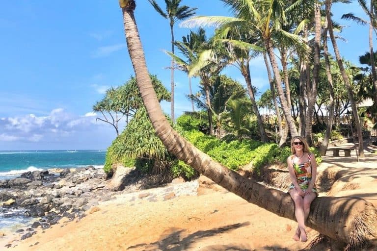 Susan Heinrich sits on a palm tree on a beach vacation in Maui