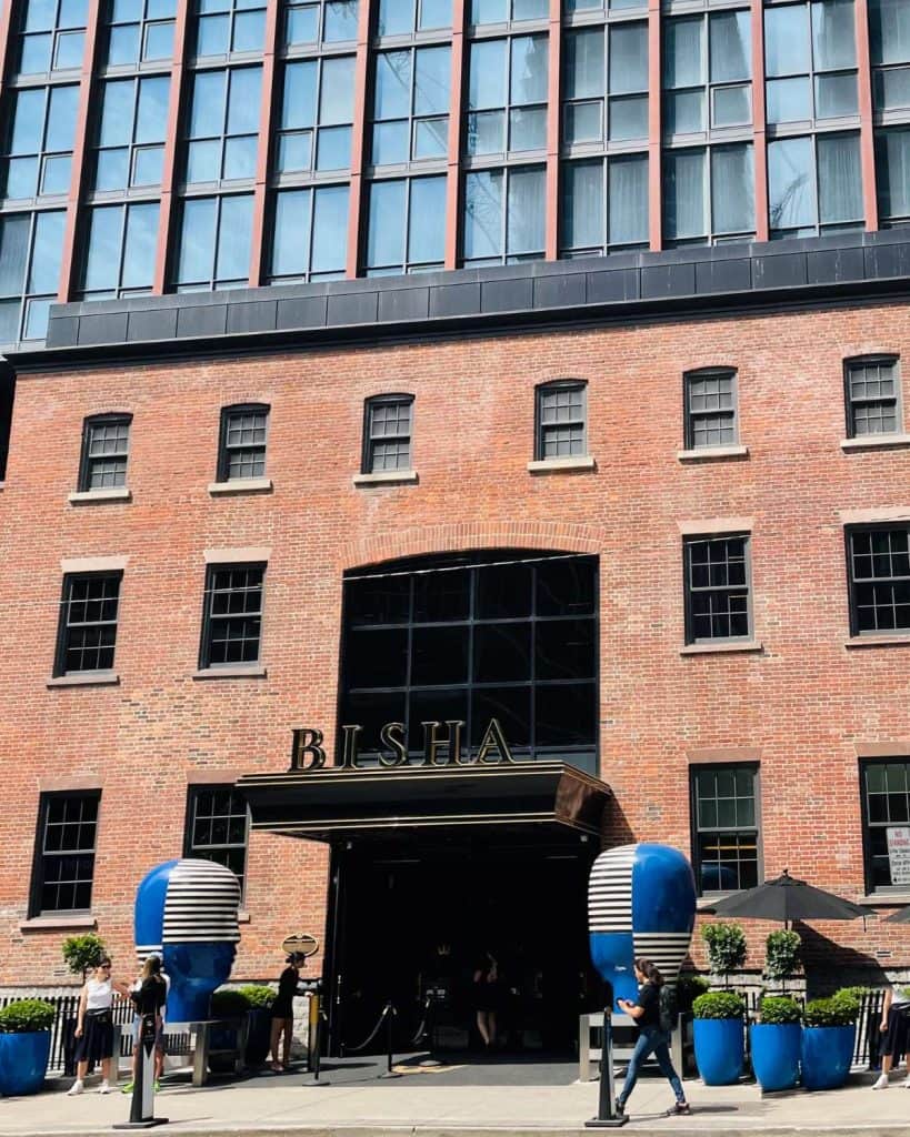 The front of the Bisha Hotel in Toronto. The exterior is a combination of modern glass and historic red brick.