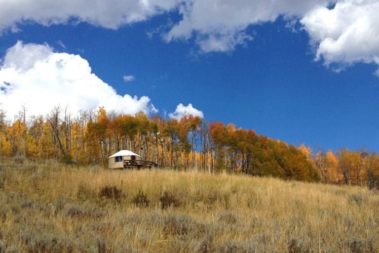 A Colorado yurt is set in a remote location with golden aspen trees beyond it