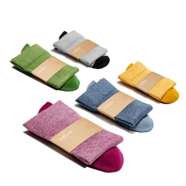 Compression socks for travel by the company Wellow. Pictures are five pairs in different colors: green, grey, pink, blue, yellow