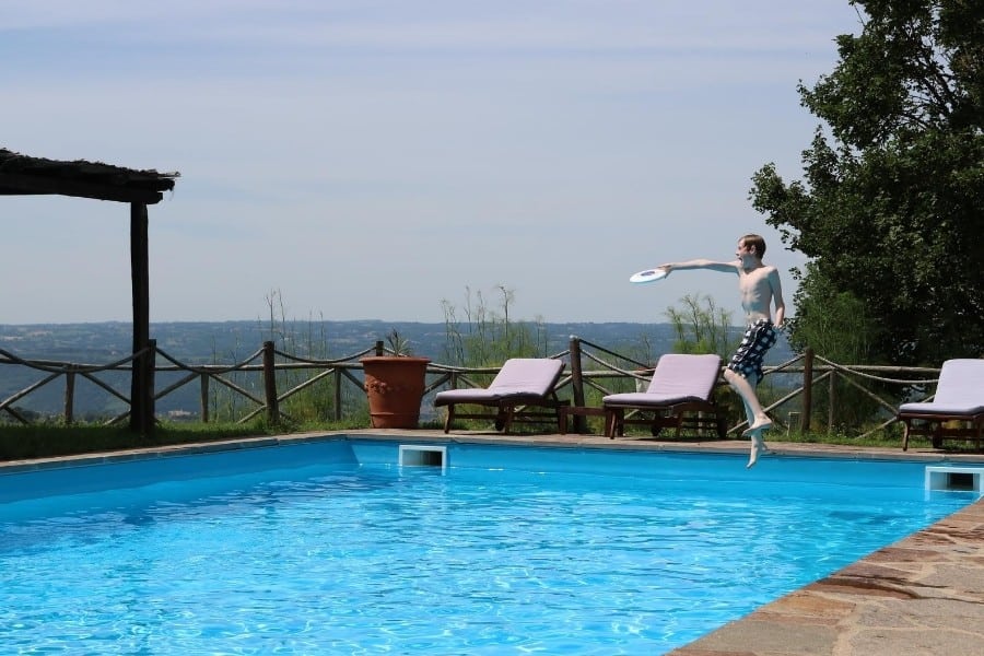 A boy plays frisbee at the swimming pool at the Umbria Agriturismo, Antica Olivaia