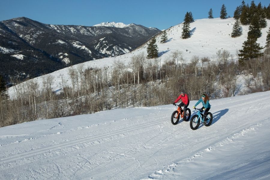 Two people ride fat bikes in winter