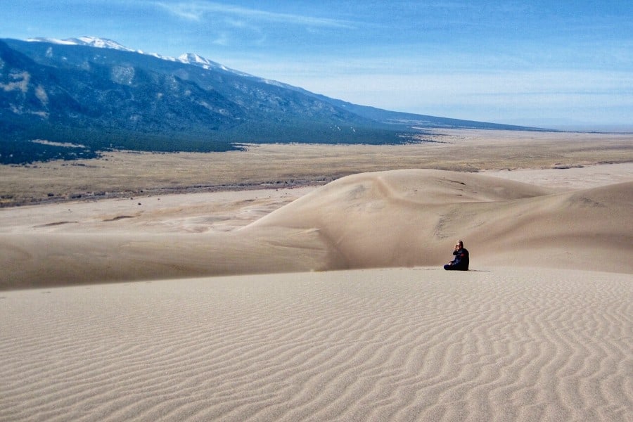 Great Sand Dunes National Park with a woman sitting atop a dune in spring.
