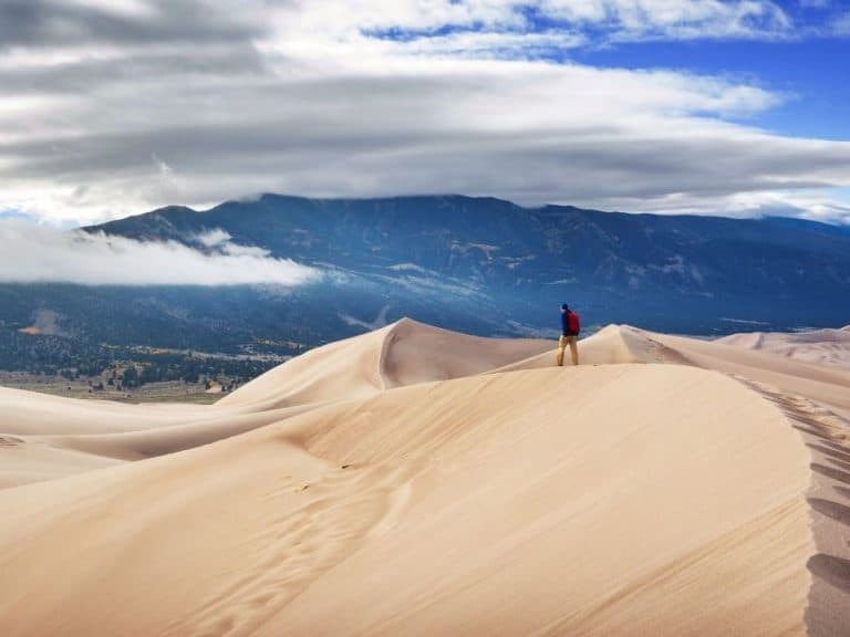 A man walks across a dune at Great Sand Dunes National Park in spring