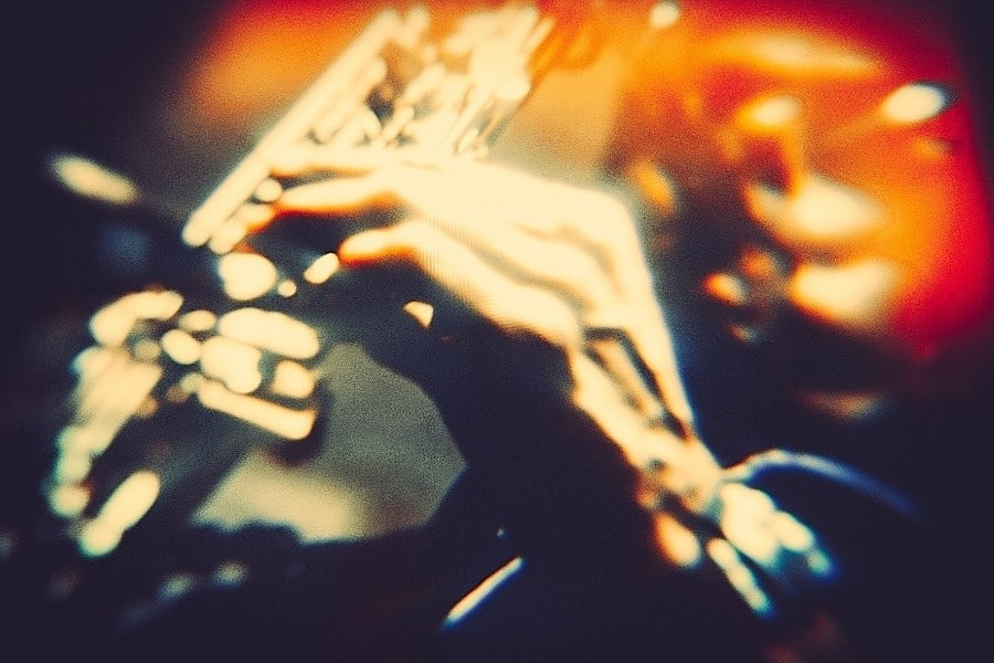 A man plays a saxaphone with orange lights beyond him
