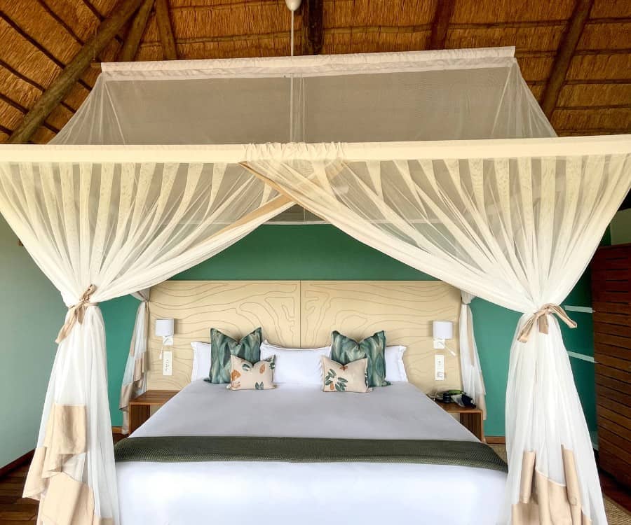 A king bed inside a thatched room chalet at Leroo La Tau safari lodge in Botswana
