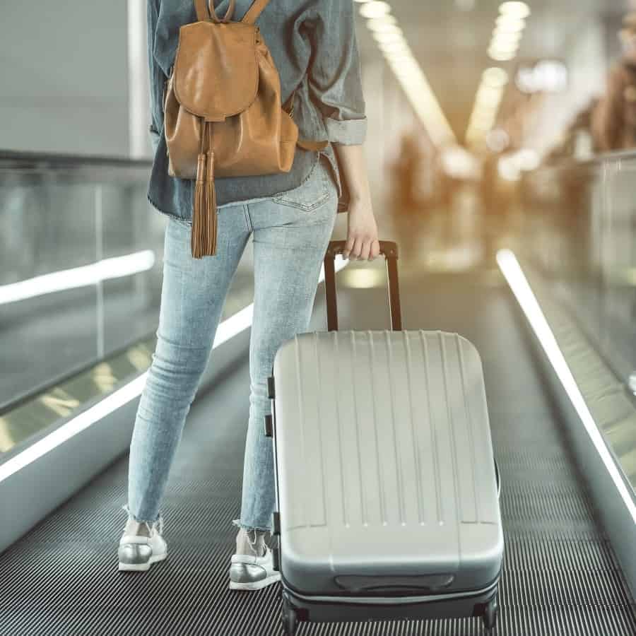 A woman holds a carry-on bin the airport