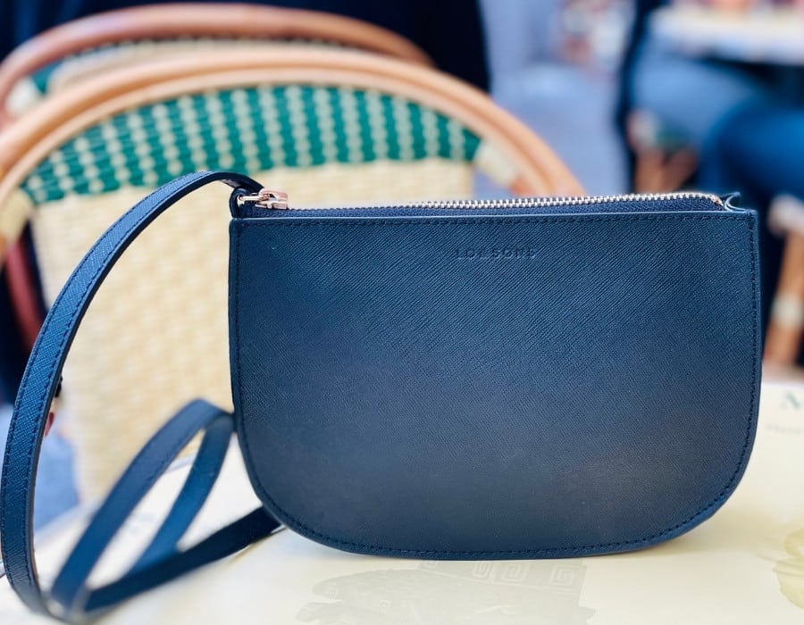 The Lo and Sons Waverley Bag sits on a café table in Paris