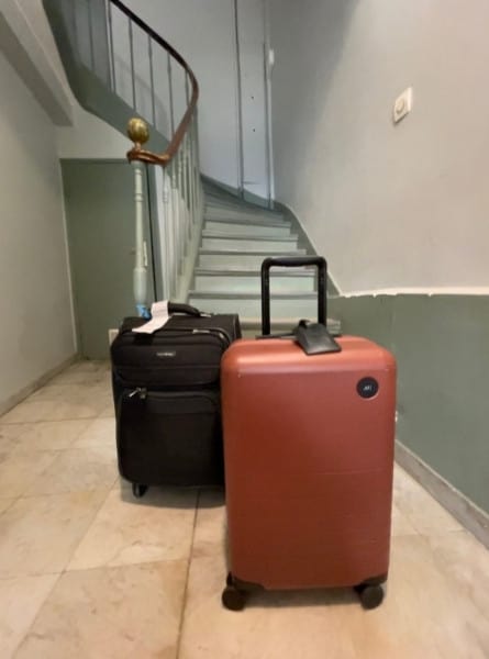 Two suitcases sit at the bottom of the a set of stairs in Paris