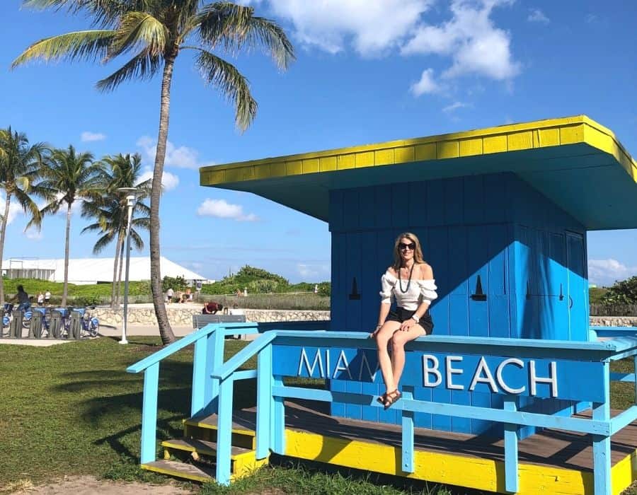 Susan Heinrich sits in a Miami Beach Lifeguard station with the beach beyond