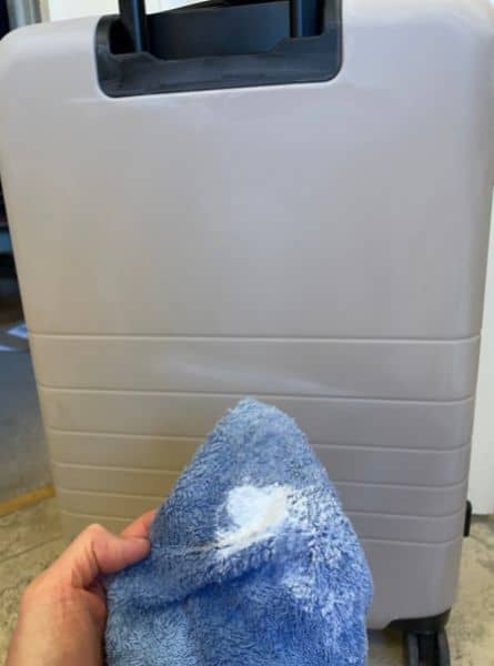 The Monos Medium checked bag in desert taupe, a light beige, pictured with a cleaning cloth with baking soda on it.