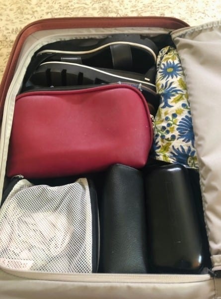 An open Monos carry-on suitcase packed with items