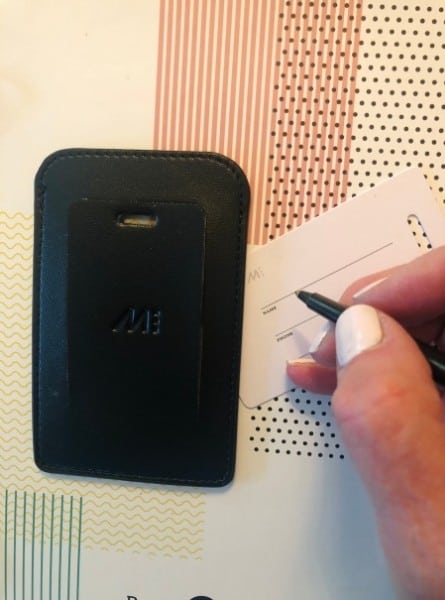 A woman's hand holds a pen to fill in a luggage tag