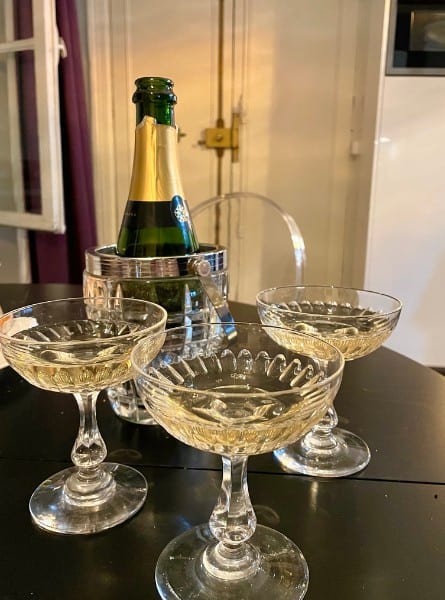 Three antique champagne coupes I purchased in Paris at Les Puces market are filled with champagne. A small bottle set in a vintage ice bucket just beyond.