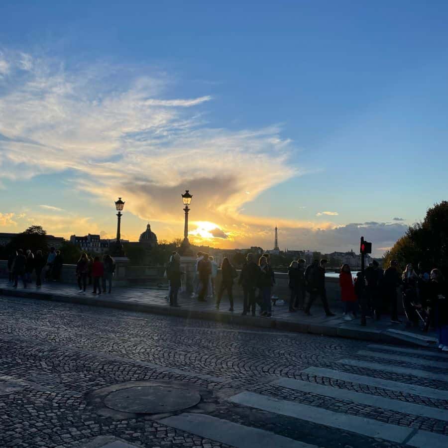 A Paris bridge at dusk with the sunset in the distance