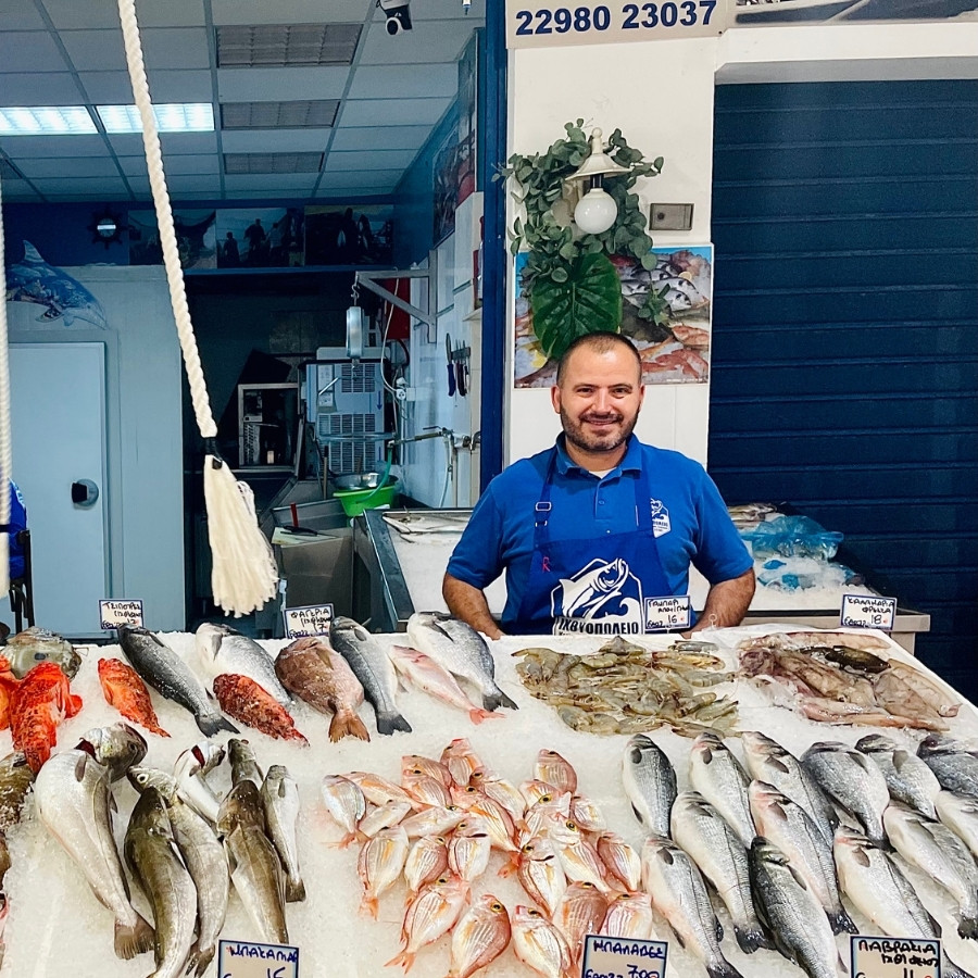 A fishmonger stands with a selection of fish in a market on the Greek island of Poros