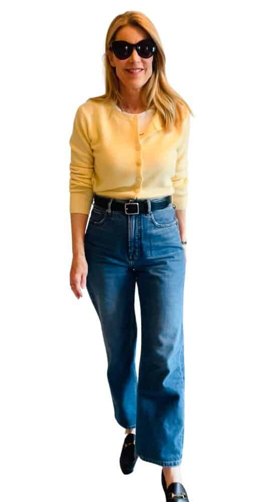 A woman wears grey trousers and a yellow cardigan