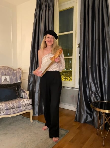 Susan Heinrich wears a beret and holds a baguette at her holiday apartment