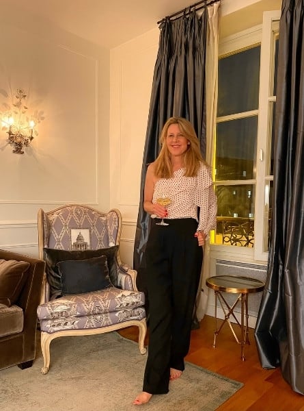 Susan Heinrich stands by the window if her paris holiday apartment with a glass of wine