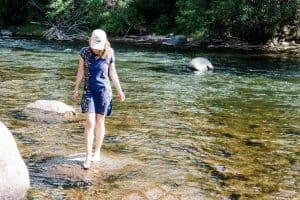 Susan Heinrich stands on a rock in a river in Beaver Creek Colorado