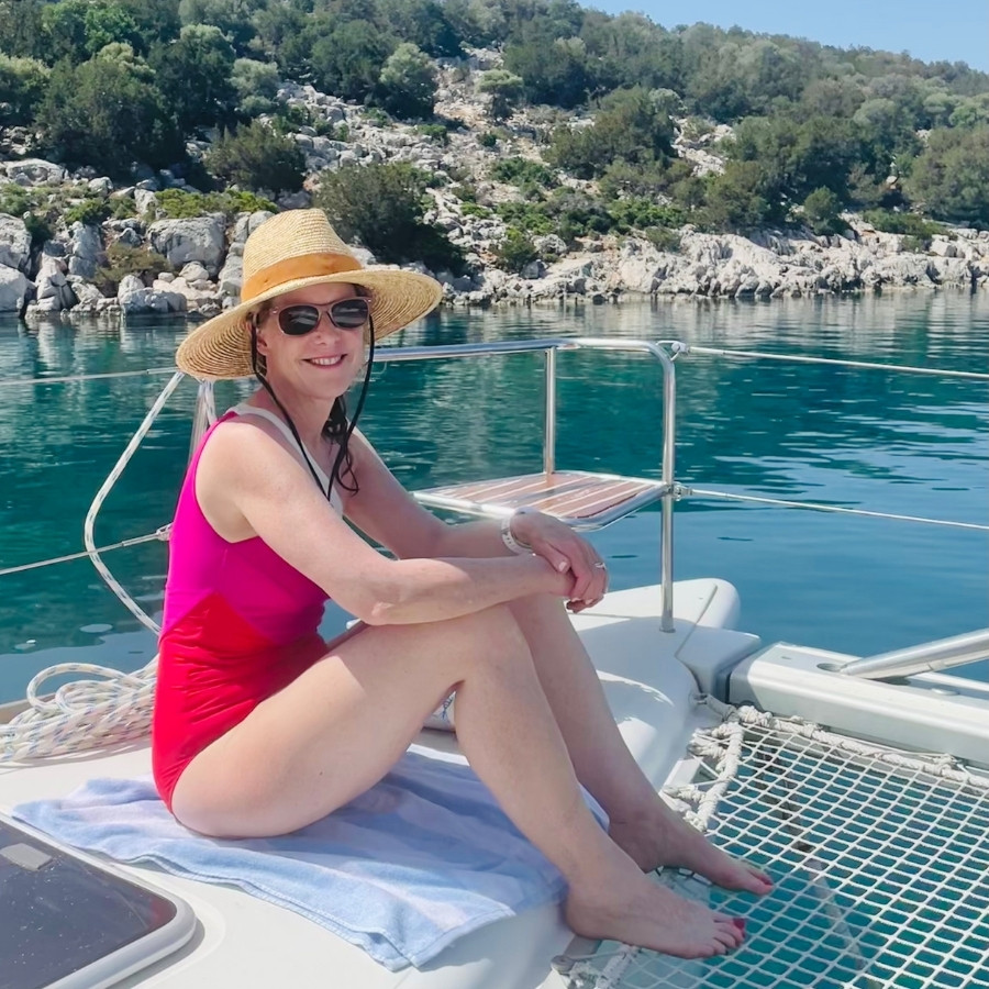 Susan Heinrich sits on a catamaran during a Greek island sailing trip with Traverse Journeys. Dokos Island Greece