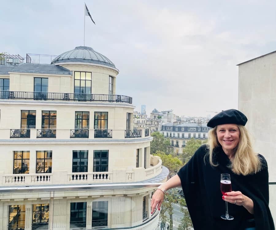Susan Heinrich stands on a outdoor terrace in Paris near the Champs Elysees