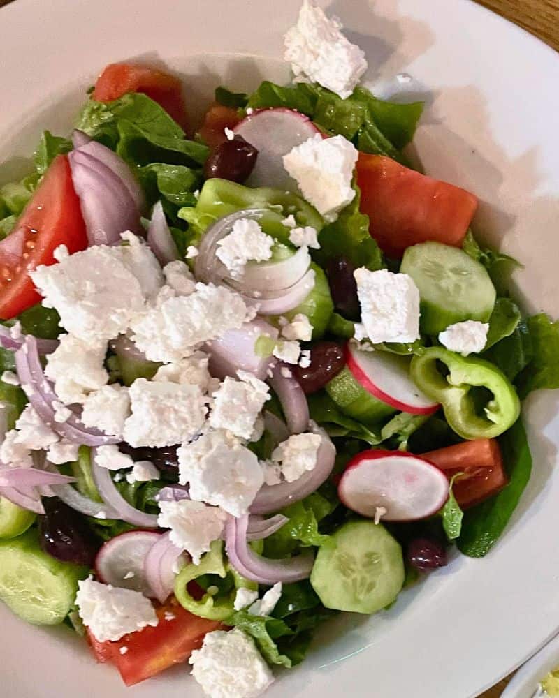 A Cypriot village salad with lettuce, cucumbers, radish, feta, onion, pepers and cilantro