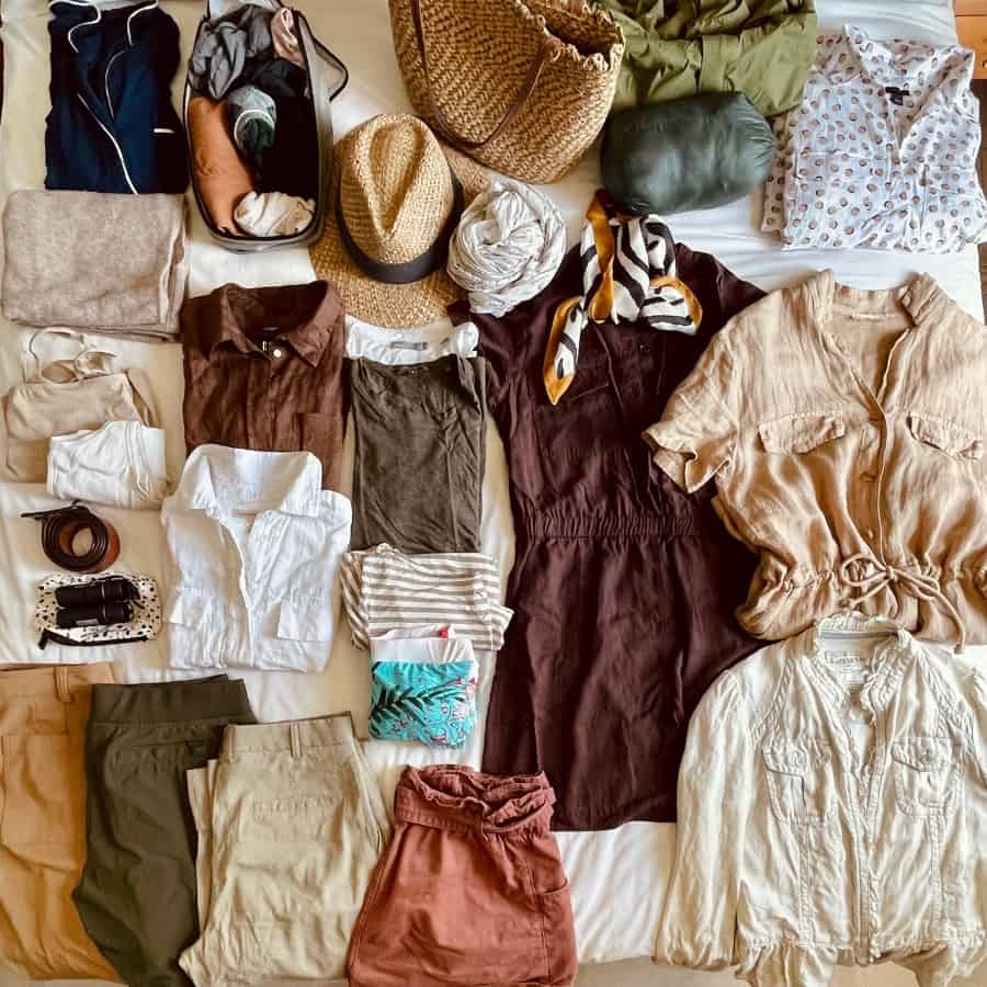 About 20 clothing items including pants, shirts, shorts, and other travel items spread out that combine to create a capsule wardrobe of African safari outfits.