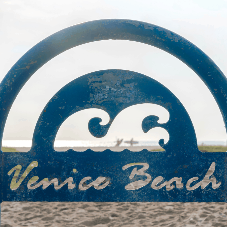 Venice Beach Sign with surfers beyond